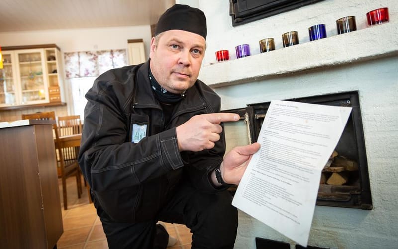 Nuohooja esittelee tarkastusraporttia takan vieressä asiakkaan kotona