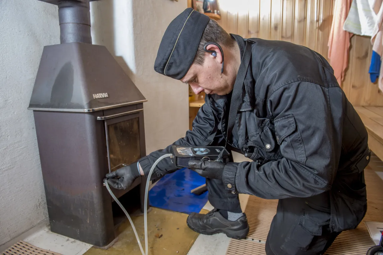 Nuohooja tarkastaa puulämmitteistä saunauunia diagnostiikkalaitteiden avulla