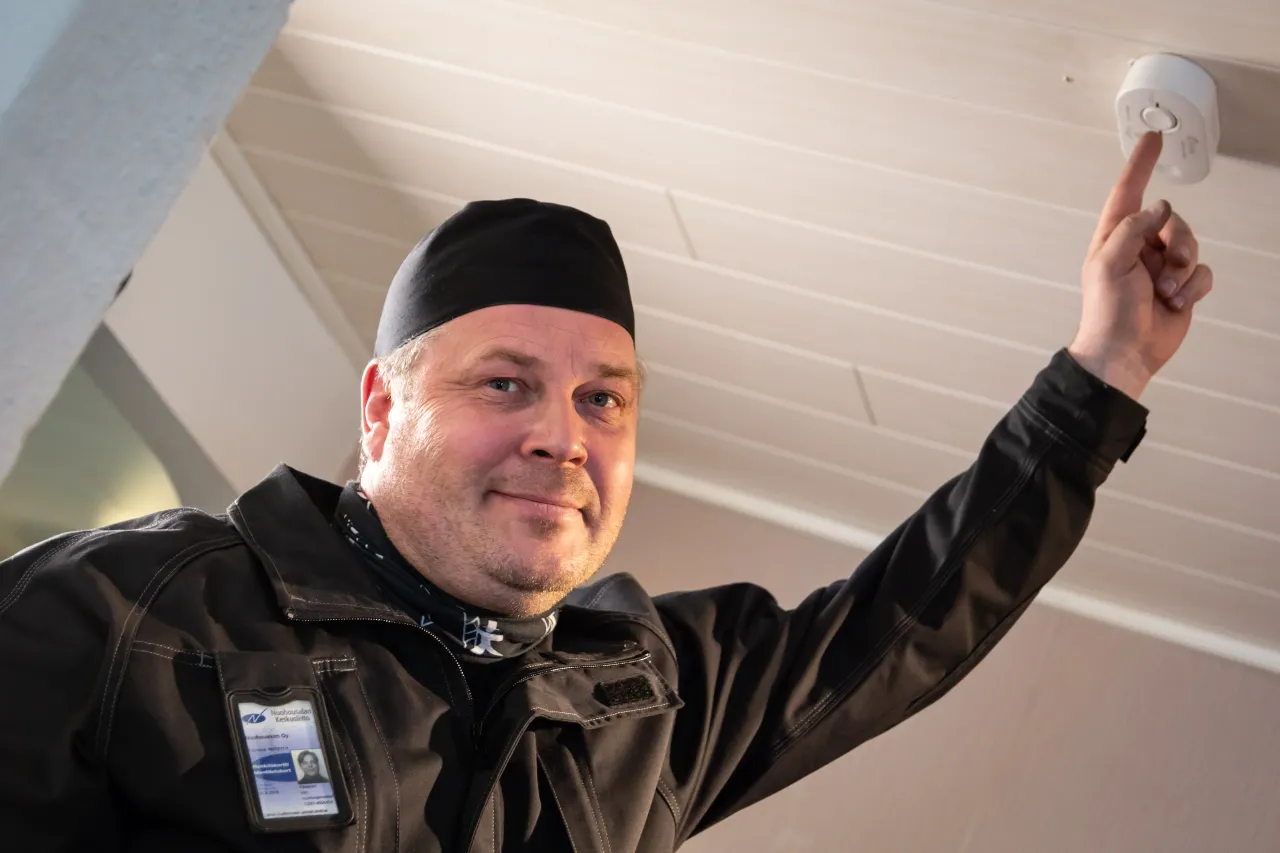 Nuohooja osoittaa kattoon asennettua palovaroitinta