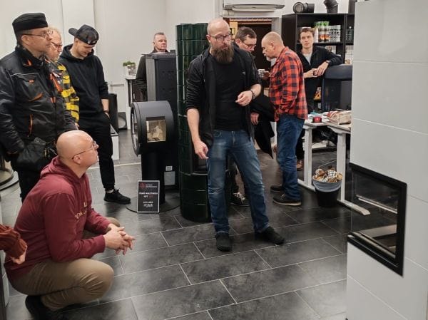 Nuohoojien ryhmä tutustumassa tulisija- ja uuni-asennuksiin näyttelytilassa